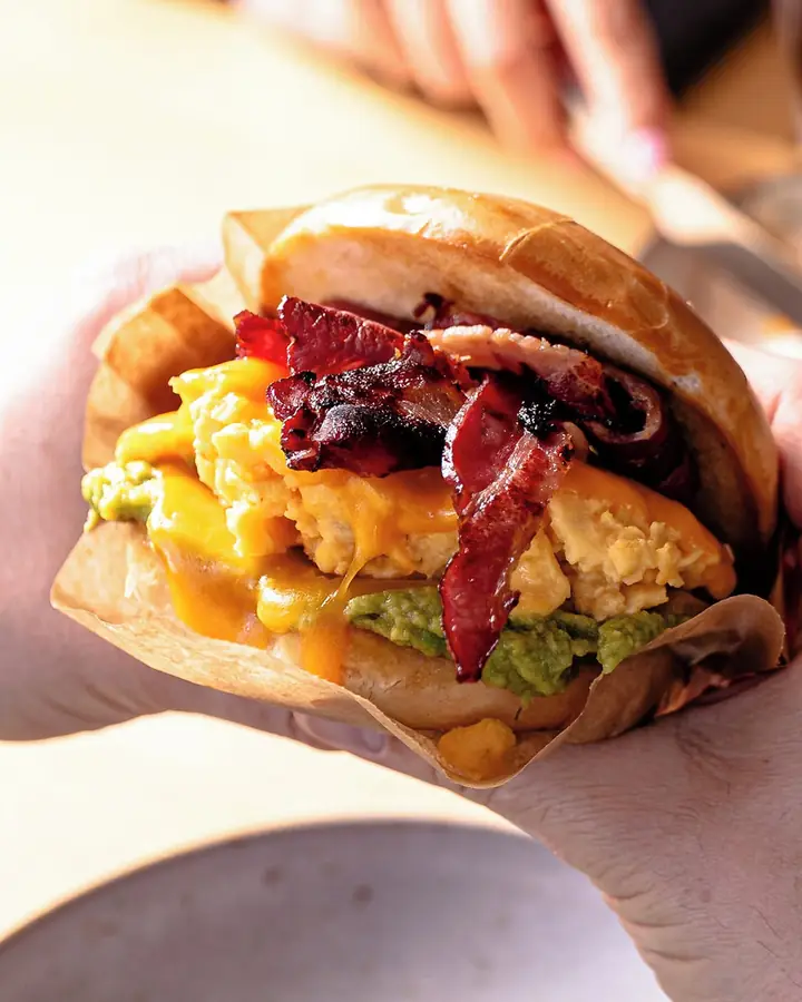Hand holding the Bag’all, with scrambled egg, bacon and avocado