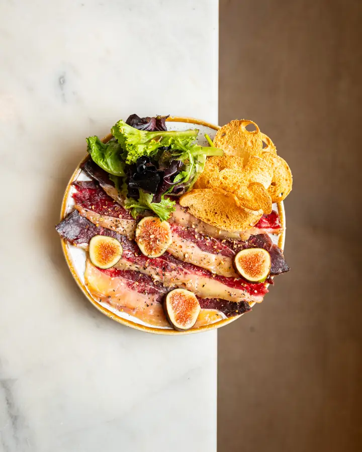 Beef carpaccio with figs, greens and toasts, seen from above