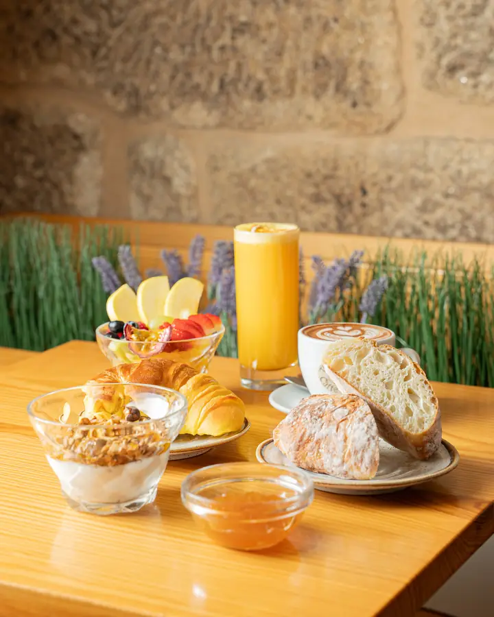 Breakfast table with yogurt and granola, fruit, bread, croissant and orange juice