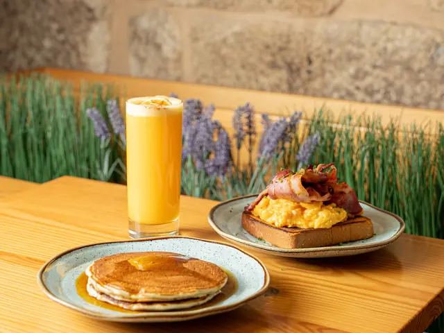 Brunch table with pancakes, scrambled eggs with bacon and orange juice