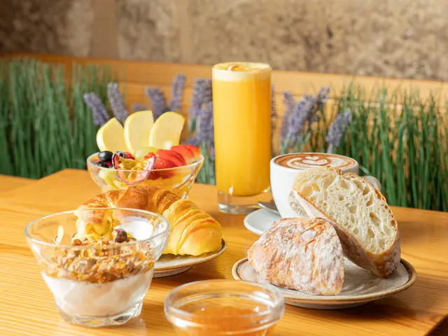 Breakfast table with yogurt and granola, fruit, bread, croissant and orange juice